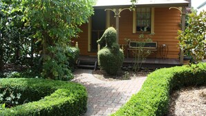 A house with a well-maintained garden, a hedge sculpture, and a brick pathway.