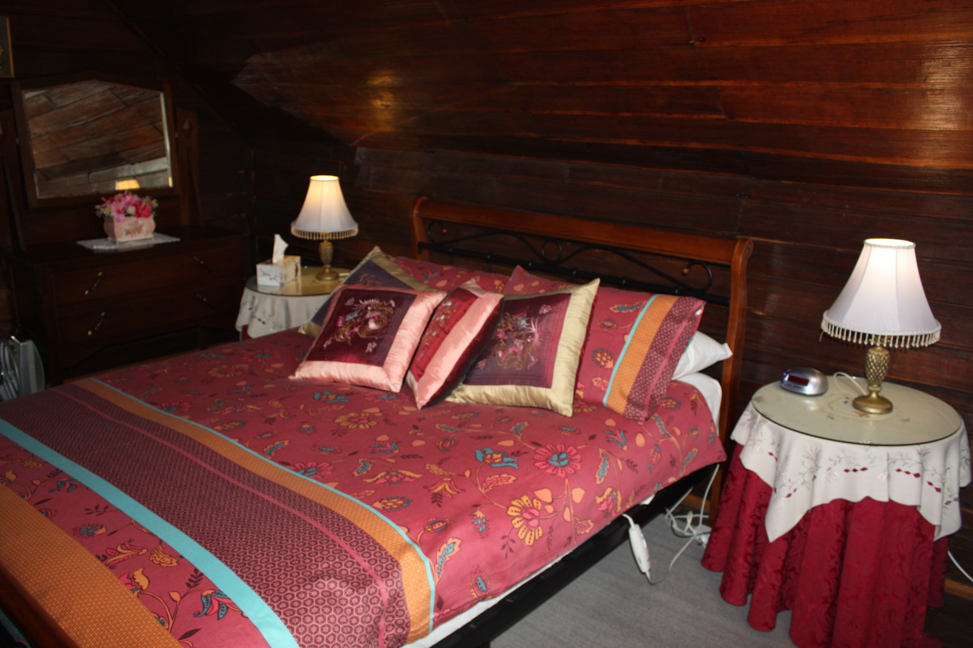 Een houten kamer met een bed, twee nachtkastjes en een lamp.