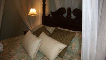 A bed with floral bedding, a canopy, and a bedside lamp.