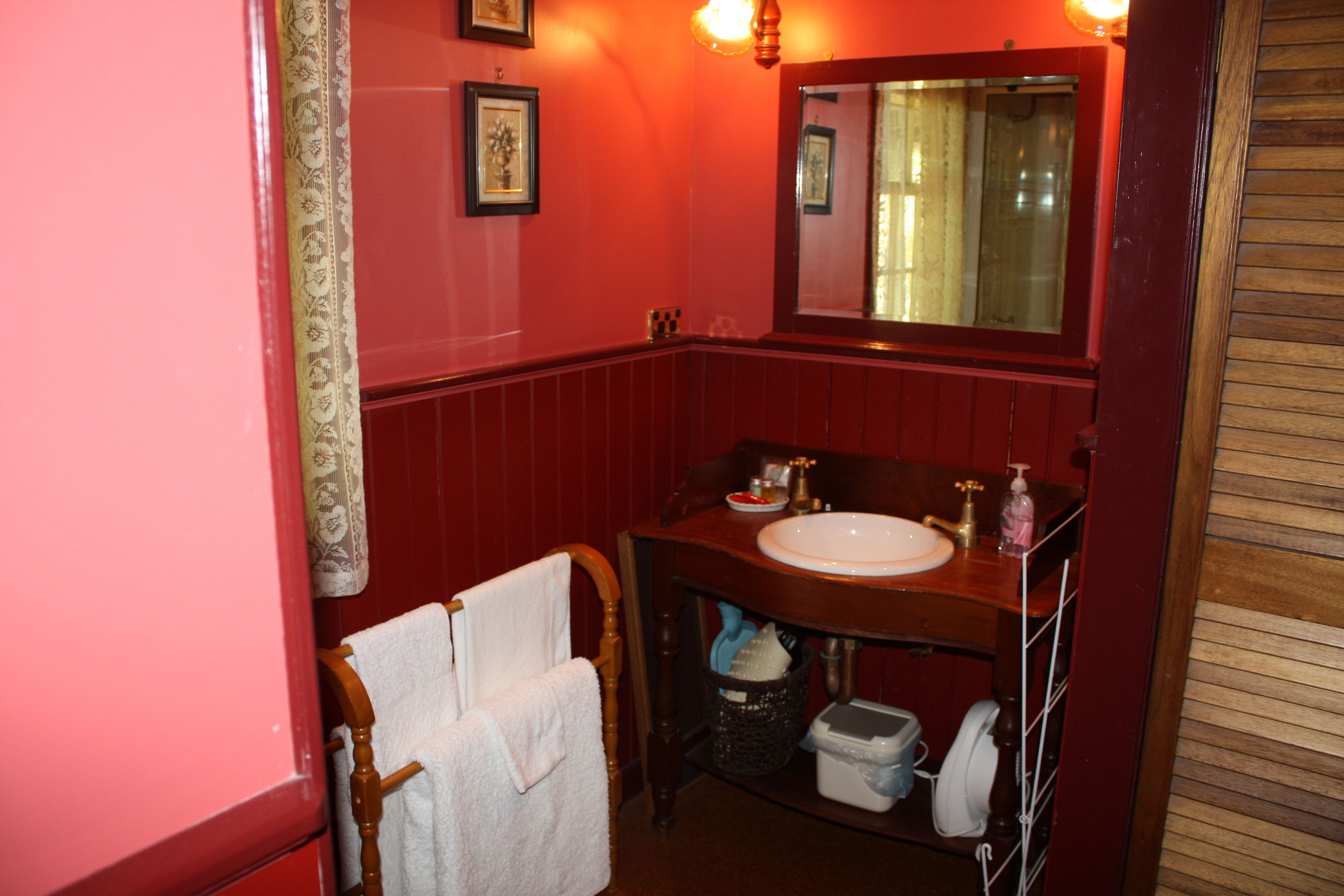 A bathroom with a wooden vanity, a white sink, a mirror, and a towel rack.