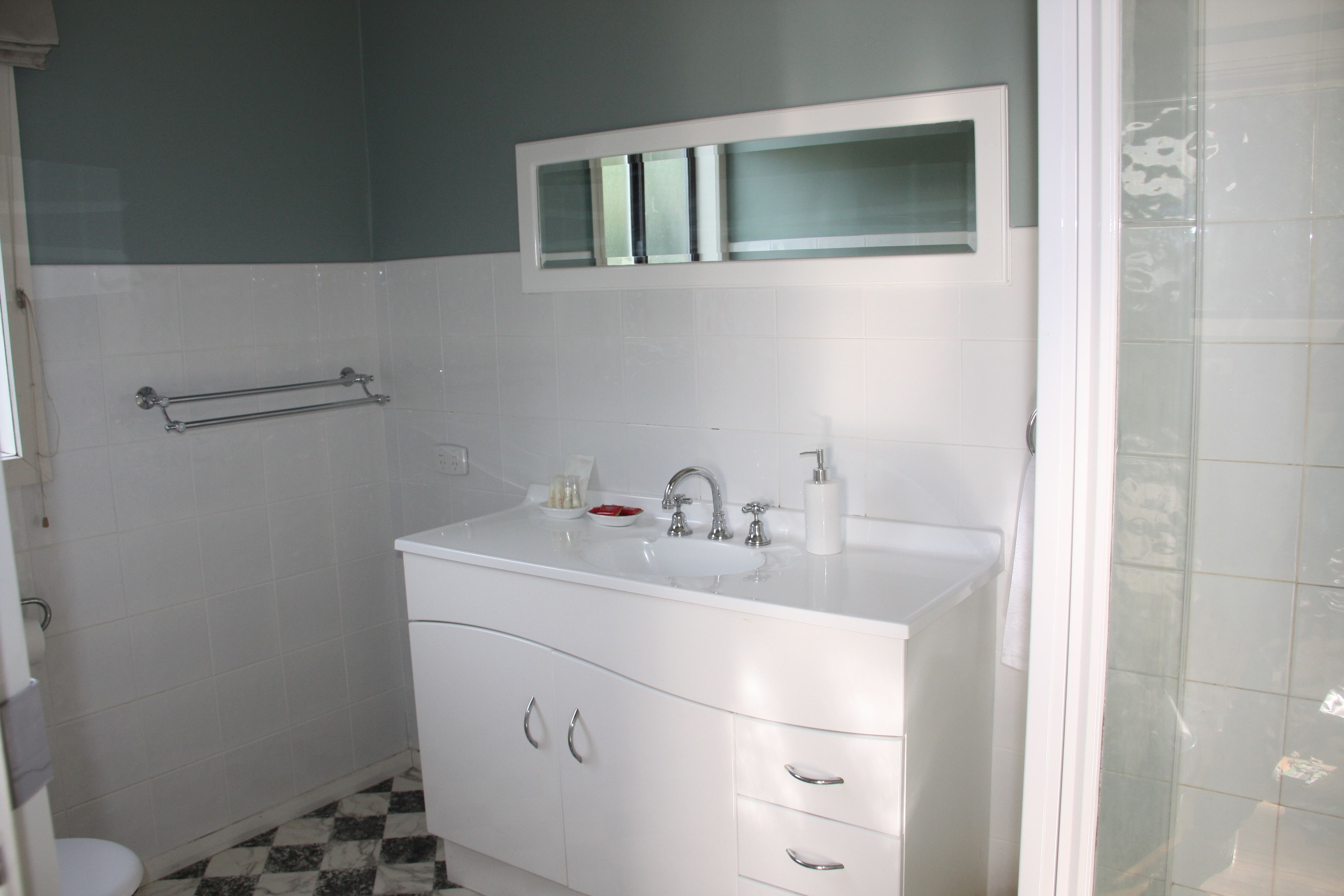 Un baño con un lavabo blanco, espejo y armarios.