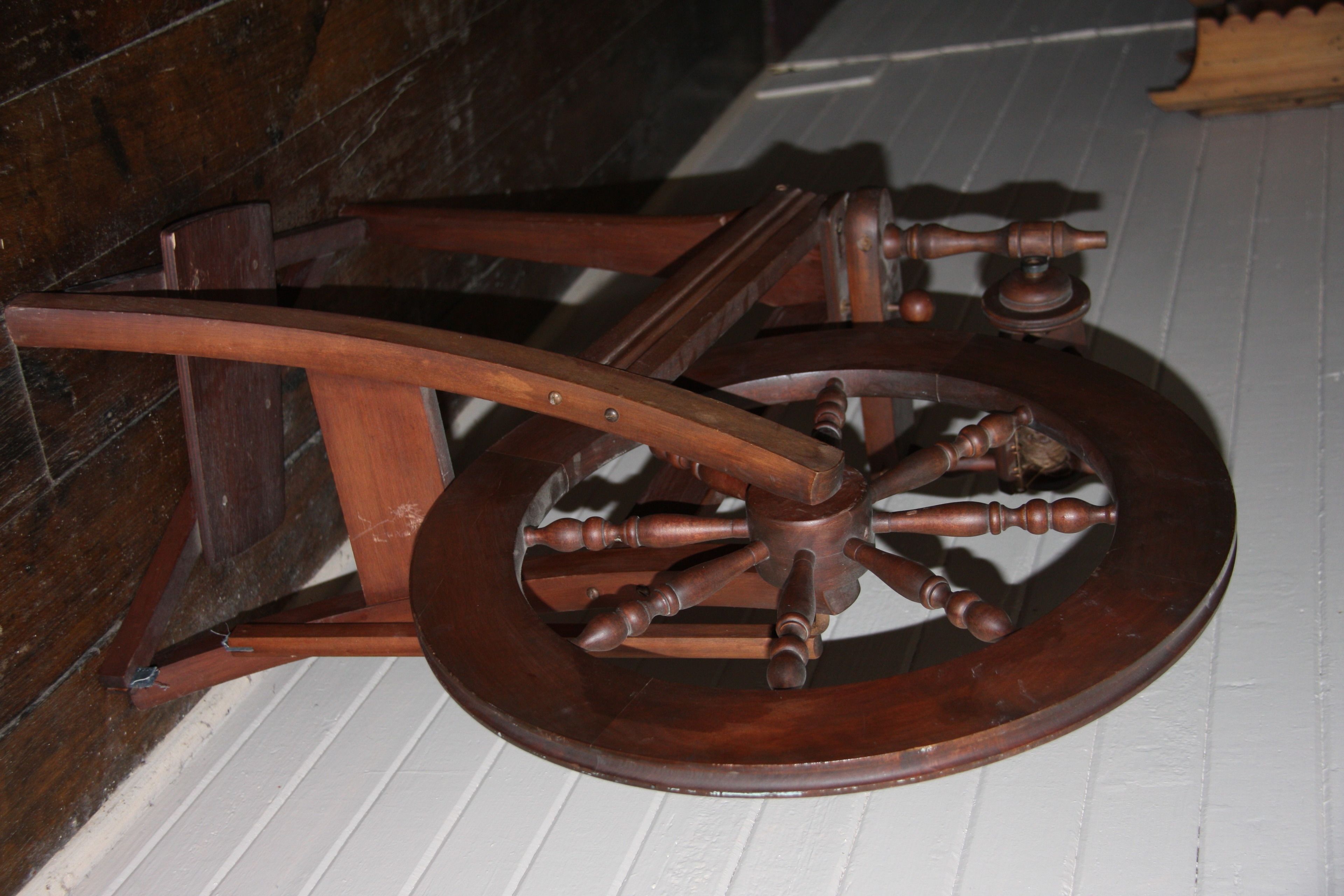 A wooden spinning wheel with a wooden frame and a central wheel.