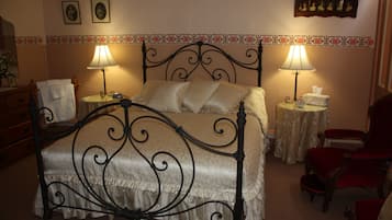 Ein ordentlich eingerichtetes Schlafzimmer mit einem Bett, zwei Nachttischen, einem Sessel und einer Kommode.