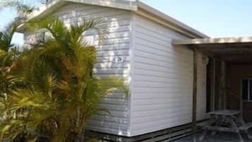 Una casa móvil de un piso con techo plano y un porche cubierto.