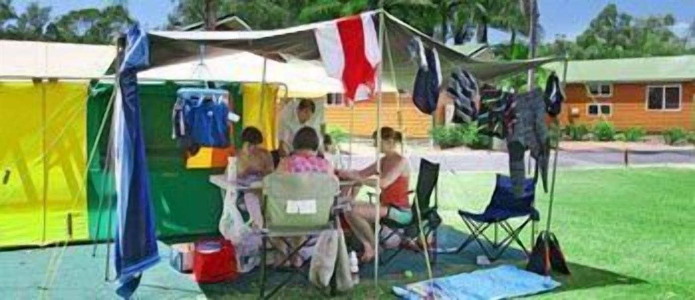 Um camping com tendas, cadeiras e uma mesa montados ao ar livre.