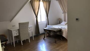 A bedroom with a bed, a desk, and a chair.
