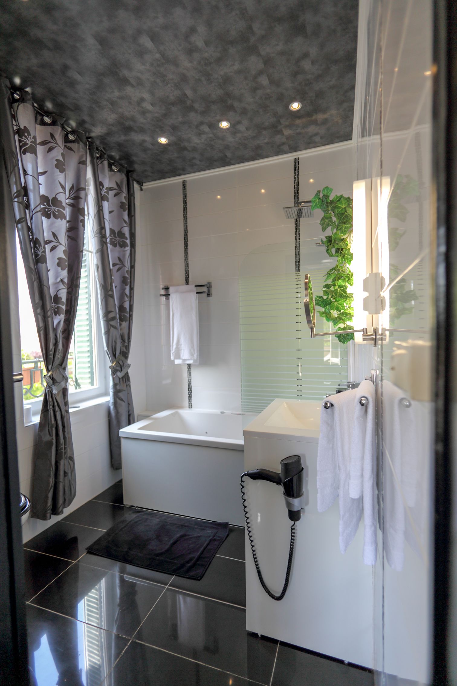 Un baño moderno con bañera, cabina de ducha con mampara de vidrio y tocador con toallero.