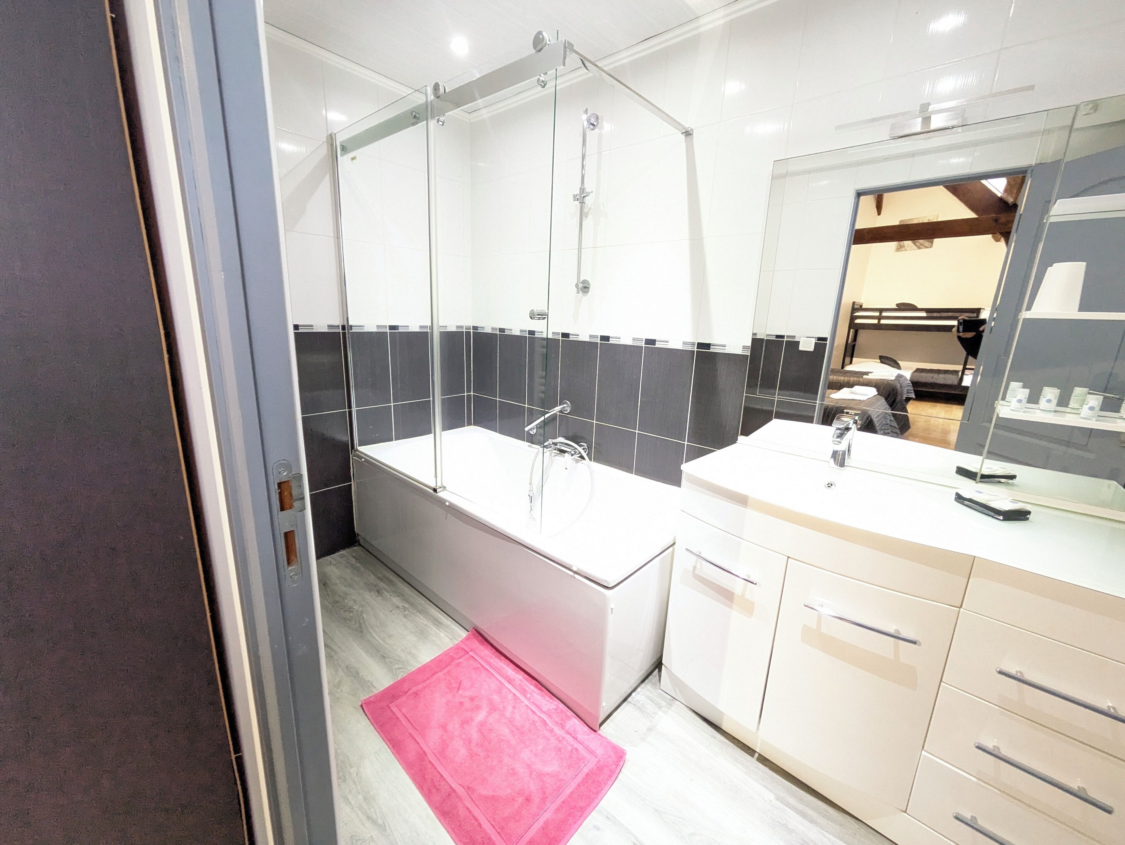 Un baño moderno con ducha de vidrio, una bañera blanca y un tocador con espejo.