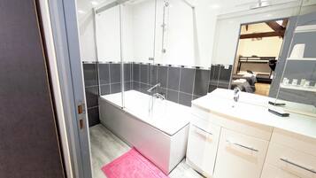 Un baño moderno con ducha de vidrio, una bañera blanca y un tocador con espejo.