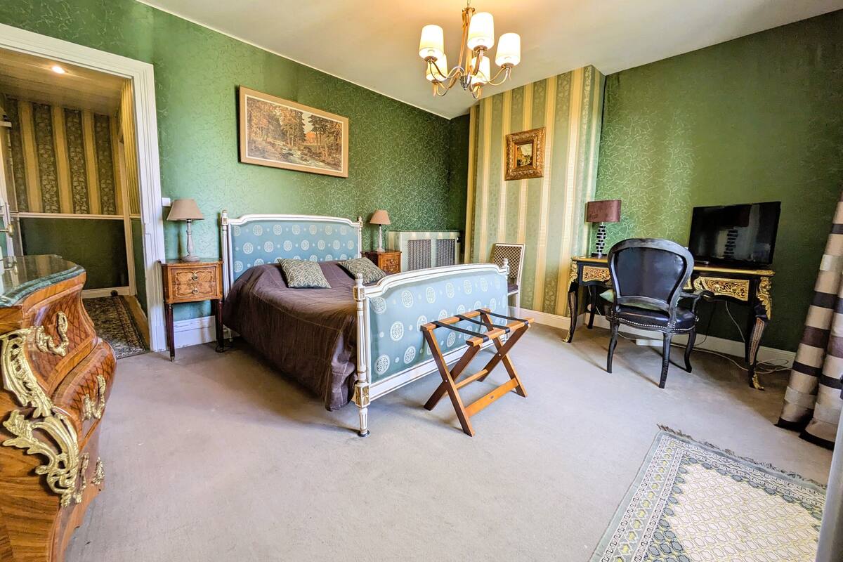 Ein Schlafzimmer mit einem Bett, einem Sessel, einem Fernseher und einer Kommode.