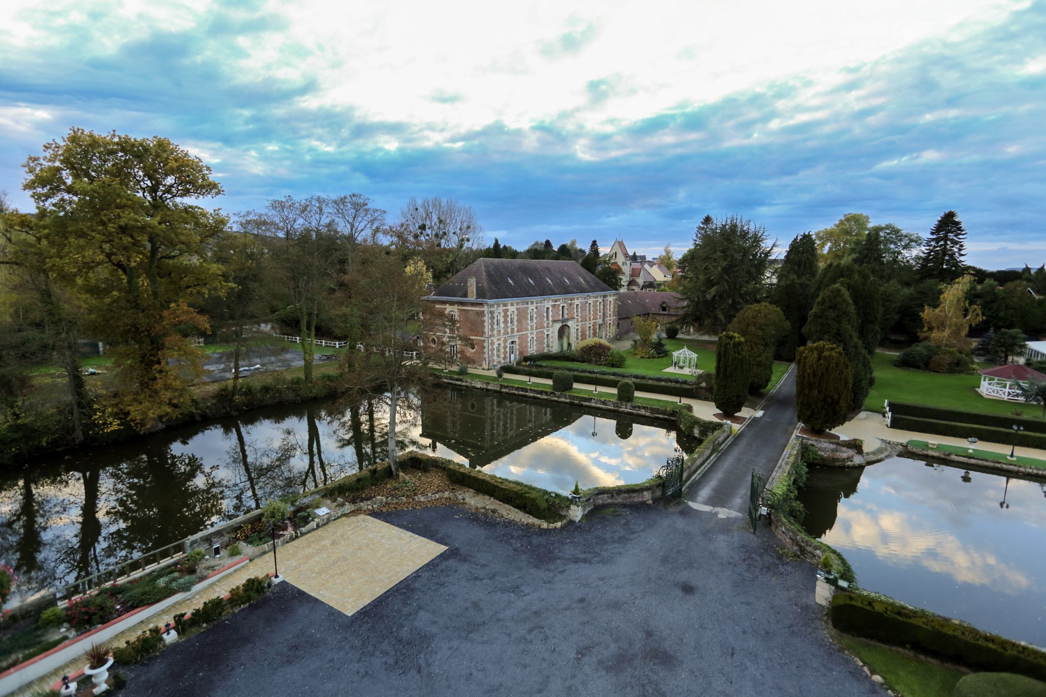Un grand bâtiment doté d’un jardin symétrique et d’un étang.