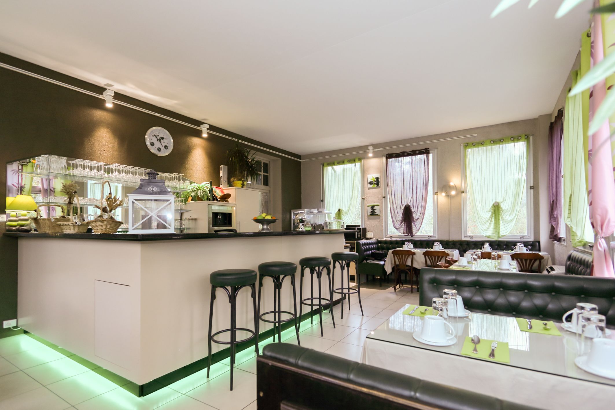 A modern kitchen with a bar area, bar stools, and a dining area with a black leather booth.