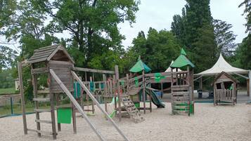 Un parque infantil con estructuras de madera, toboganes y zonas de escalada.