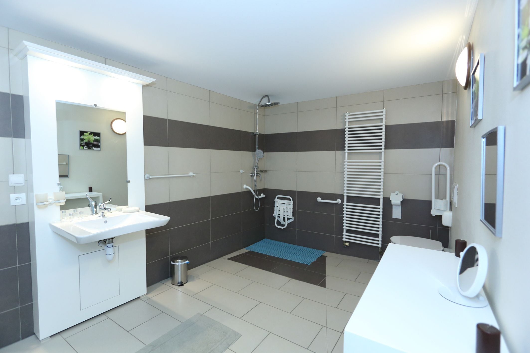 Une salle de bain moderne avec un lavabo, un miroir et des toilettes blancs, un espace douche et un porte-serviettes.
