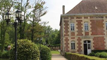 A brick building with a paved pathway leading to a pond.