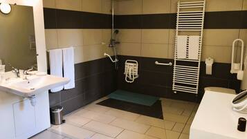 A bathroom with a sink, mirror, shower, and towel rack.