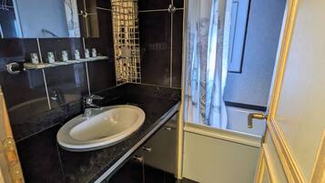 Un bany modern amb terra de rajoles negres, un lavabo blanc i una cabina de dutxa de vidre.