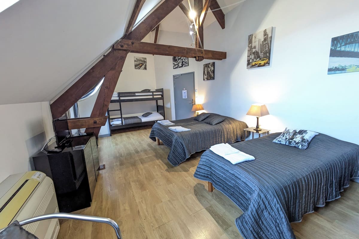 Ein Schlafsaalzimmer mit Etagenbetten, einem Schreibtisch und einem Stuhl. Es gibt zwei Nachttische mit Lampen.