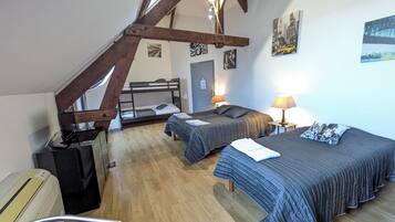 A dormitory room with bunk beds, a desk, and a chair. There are two bedside tables with lamps.