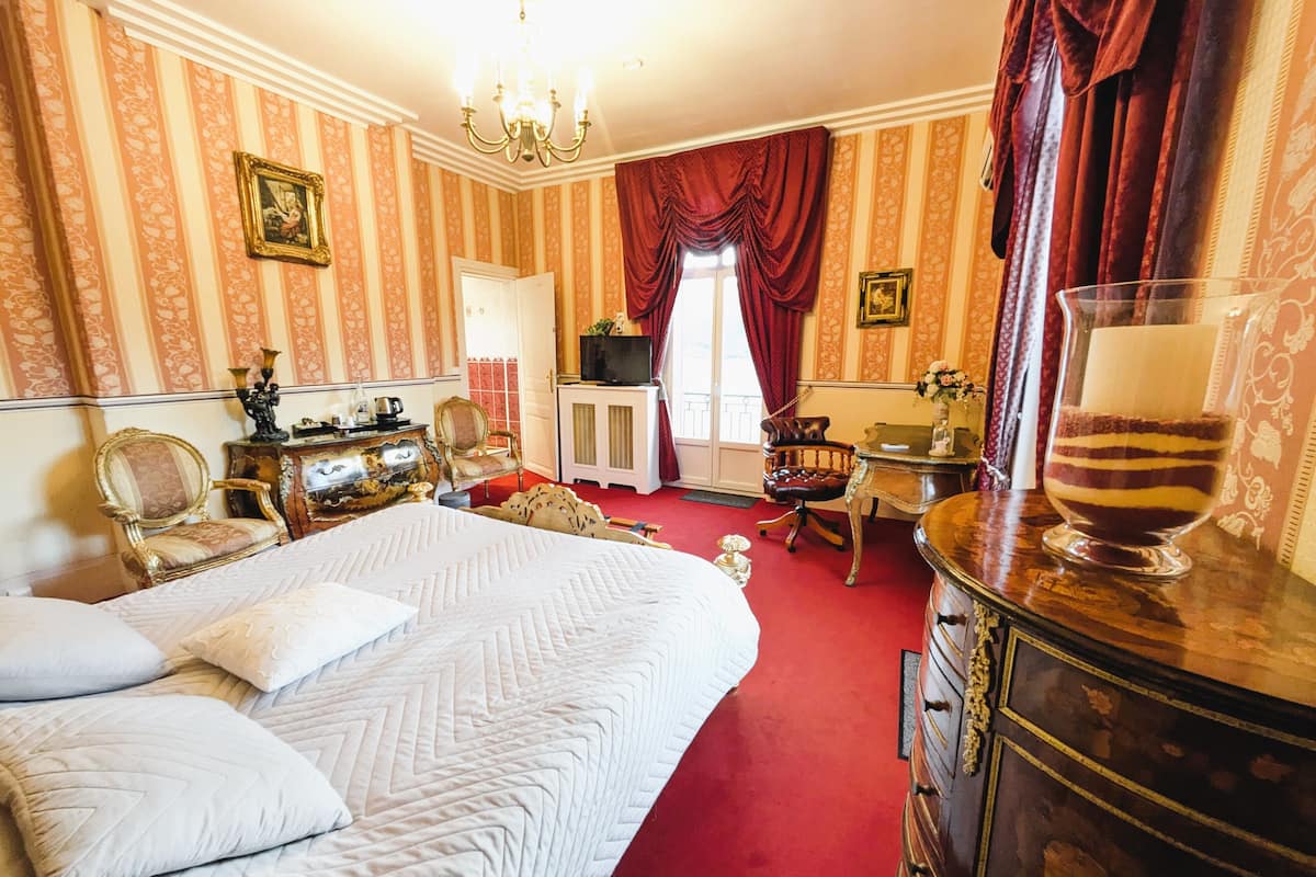 Ein Hotelzimmer mit einem großen Bett, einem Holzkapuzenpaneel, einem Schreibtisch, einem Stuhl, einem Fernseher und einem Fenster mit Vorhängen.