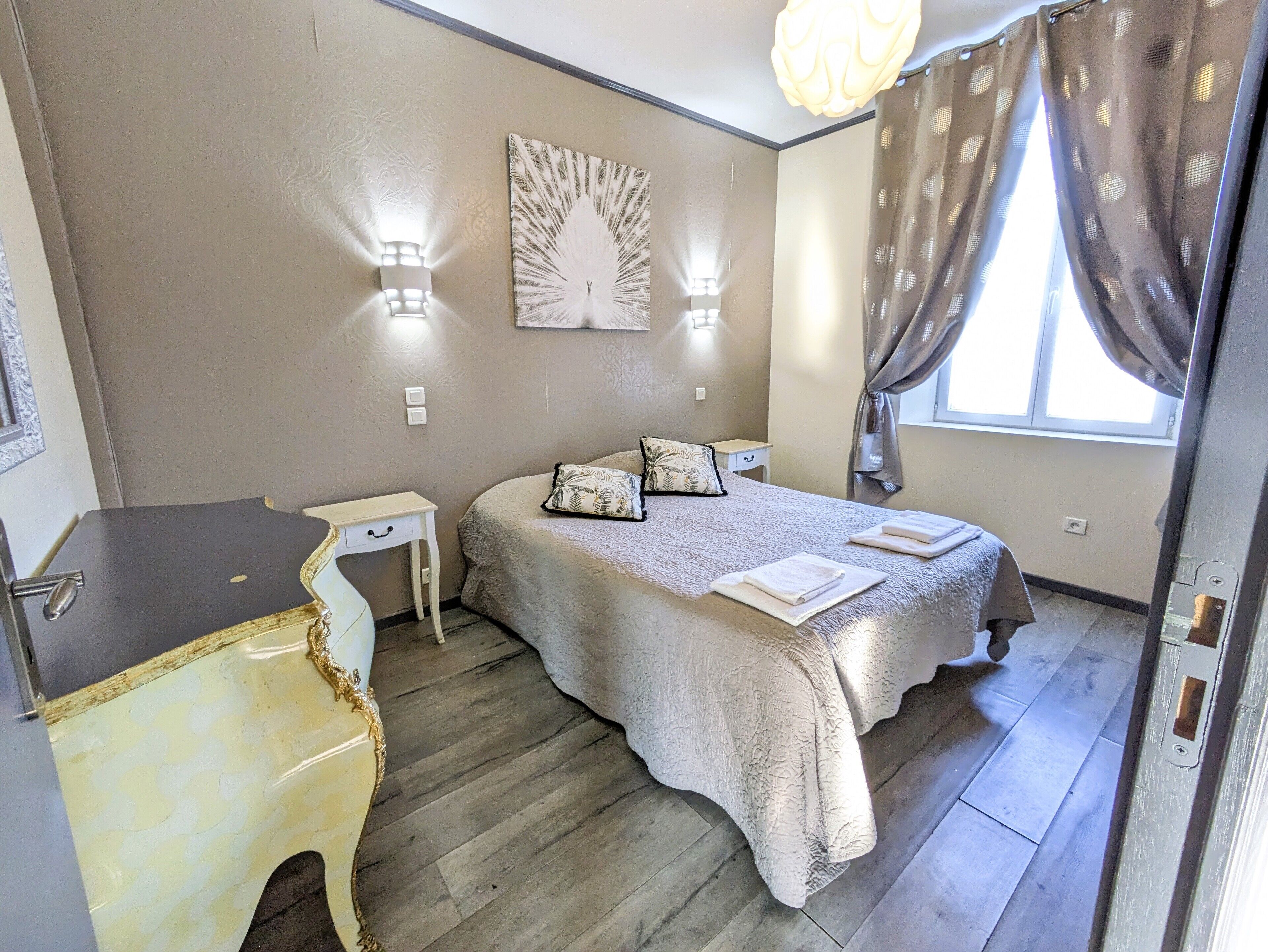 A bedroom with a bed, bedside tables, a dresser, and a window with curtains.