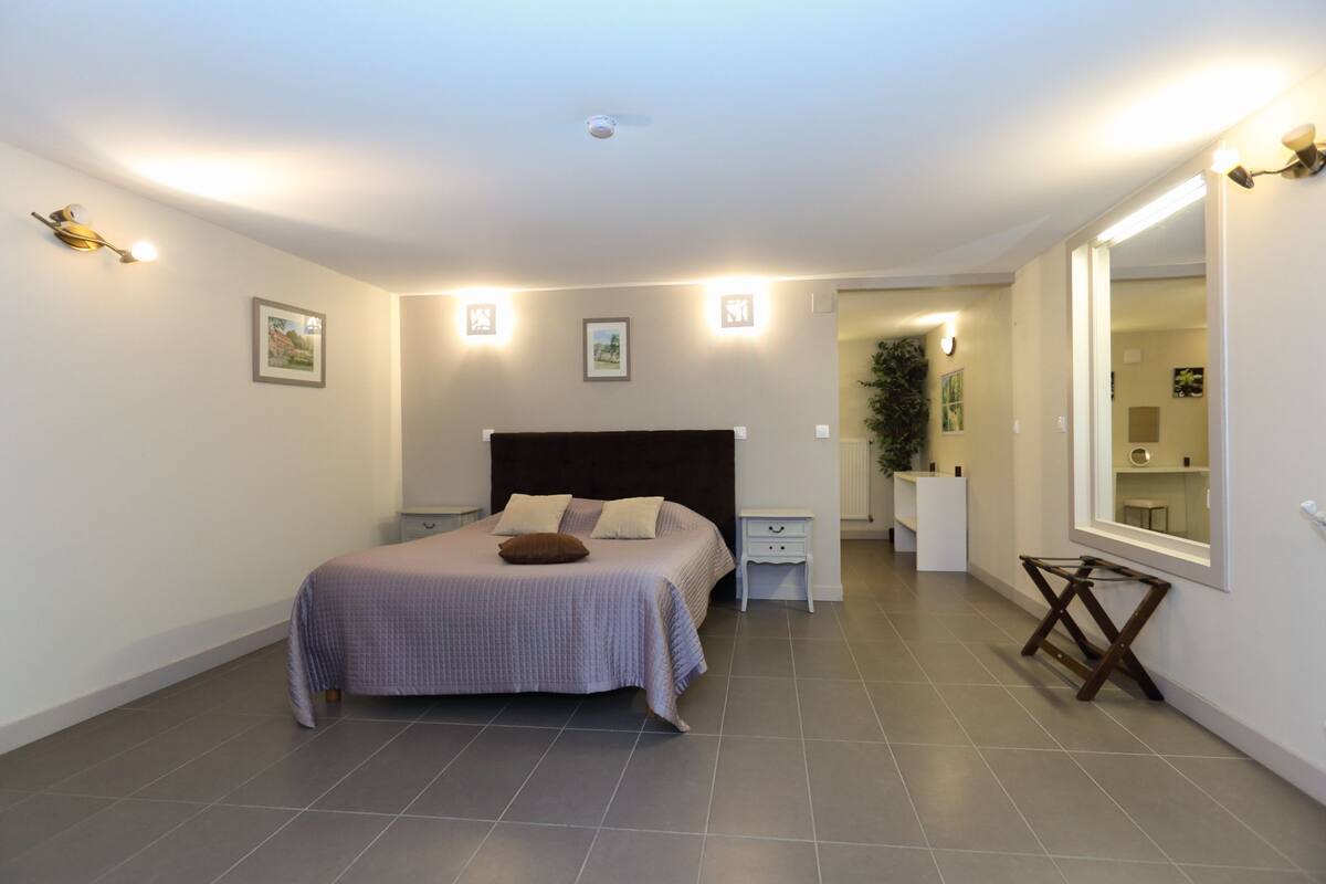 Ein Schlafzimmer mit Bett, Nachttischen, einem Spiegel und einer kleinen Pflanze.