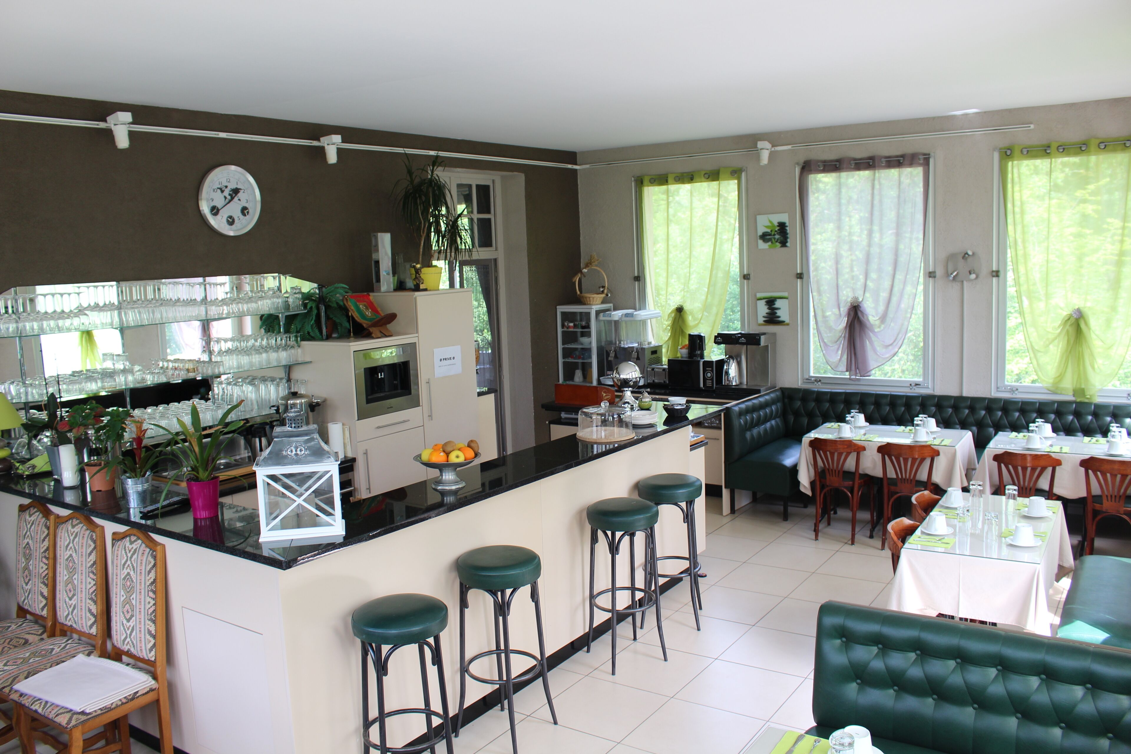 A spacious kitchen with a bar area, seating for dining, and a green upholstered sofa.