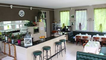 A spacious kitchen with a bar area, seating for dining, and a green upholstered sofa.