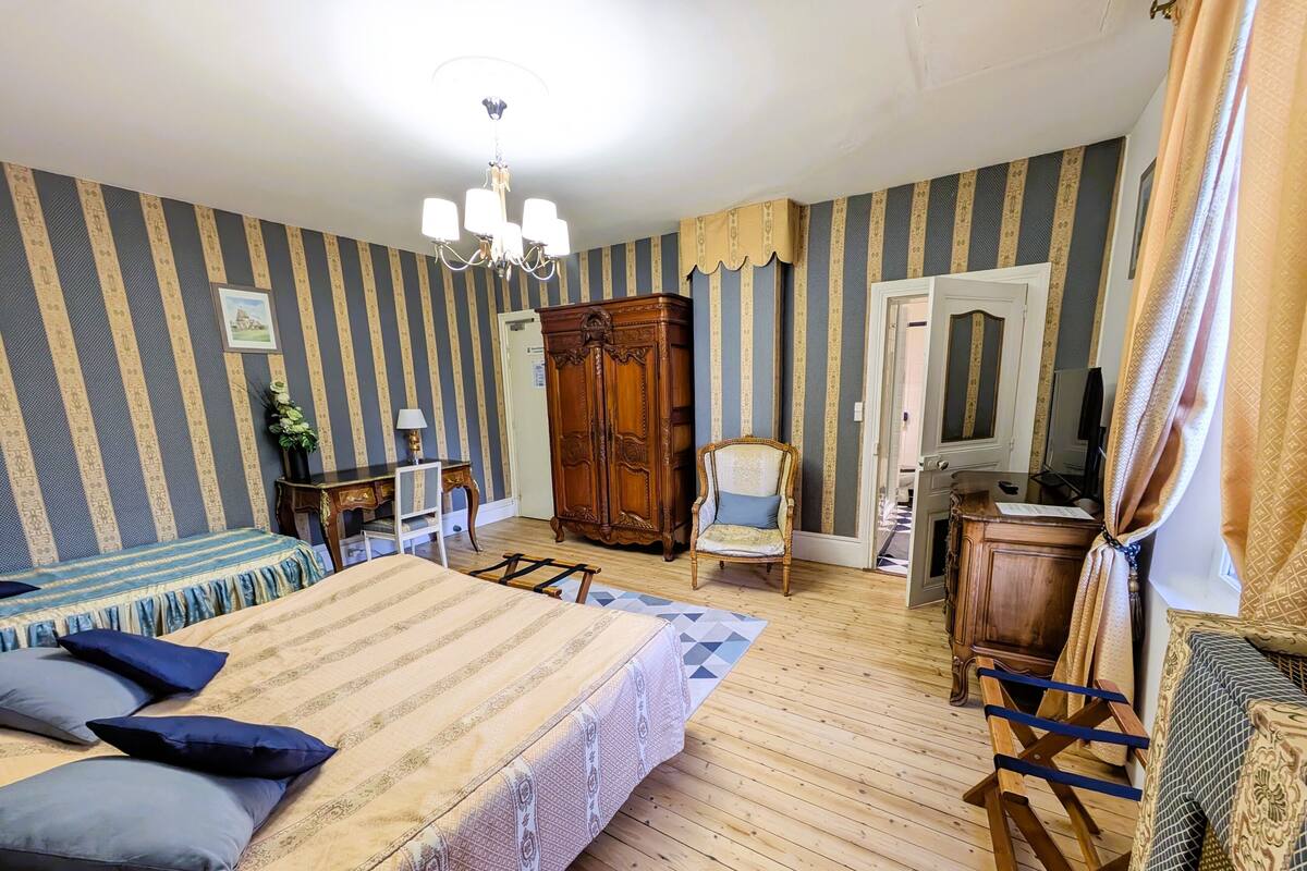 Ein Schlafzimmer mit einem großen Bett, einem Holzschrank, einem Sessel und einem Schreibtisch.