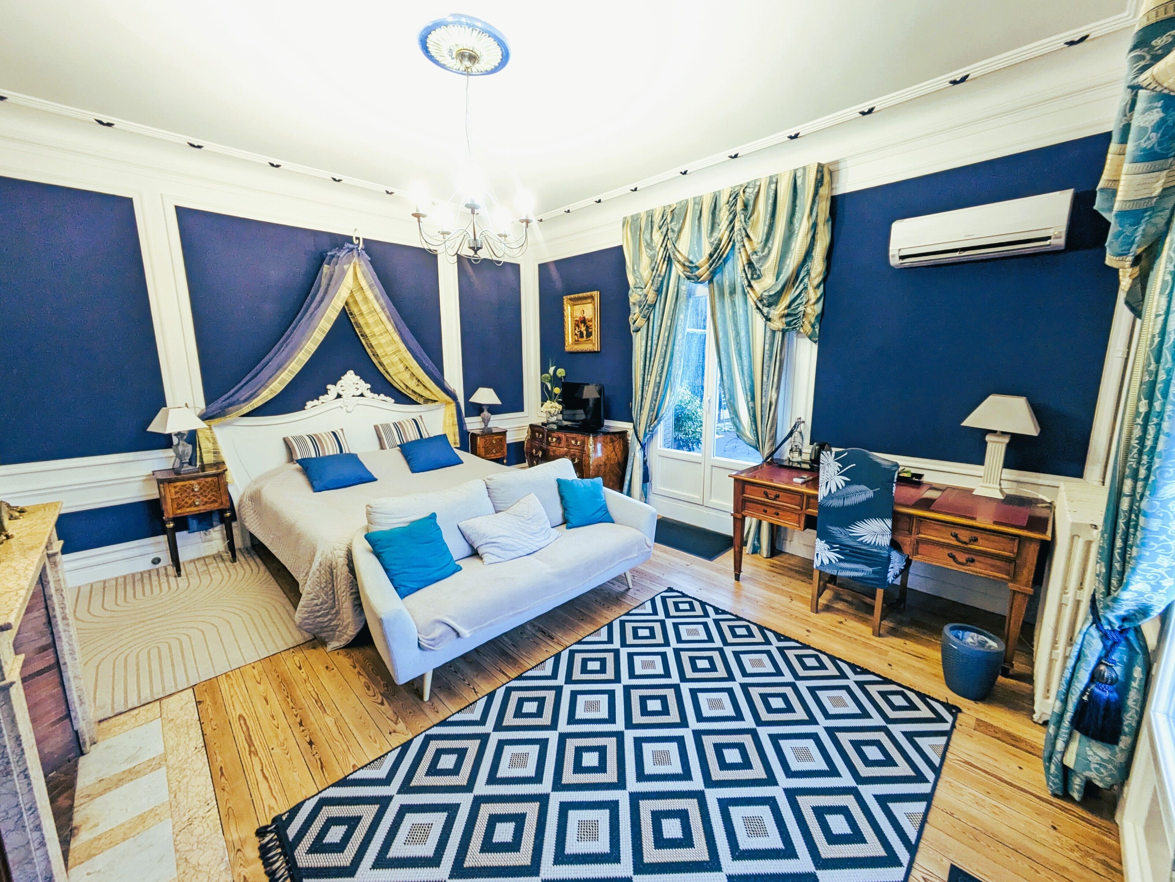 Een slaapkamer met een groot bed, een tapijtend met patroon, een bureau en een stoel.
