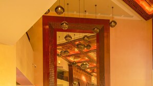 A spacious lobby with modern furnishings, a large mirror, and a ceiling with intricate designs.