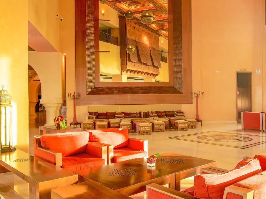 A spacious lobby with modern furnishings, a large mirror, and a ceiling with intricate designs.