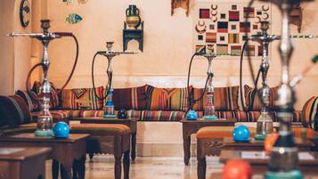 Un salón tradicional con sofá, mesas de madera y varios cachimbos.