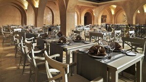 A spacious dining area with high arched ceilings and multiple tables set for dining.