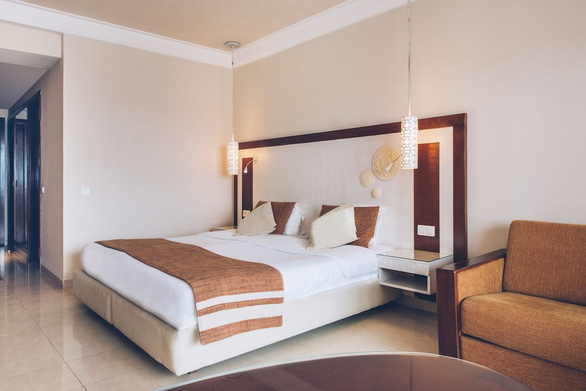 Una habitación de hotel moderna con una cama grande, una mesita de noche y un sofá.