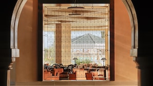 An arched doorway with a decorative metal screen, a tiled floor, and a view of outdoor furniture.