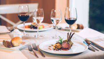 A dining table with plates of food, wine glasses, and cutlery.