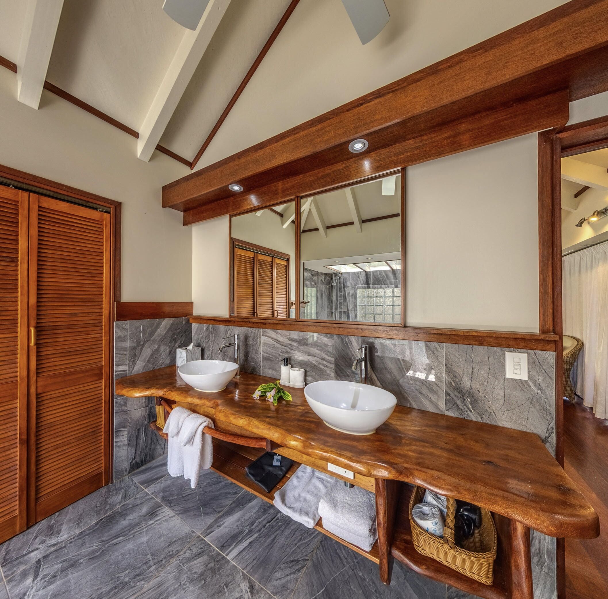 Un bagno con un mobile bagno in legno, due lavabi, uno specchio grande e uno spazio doccia.