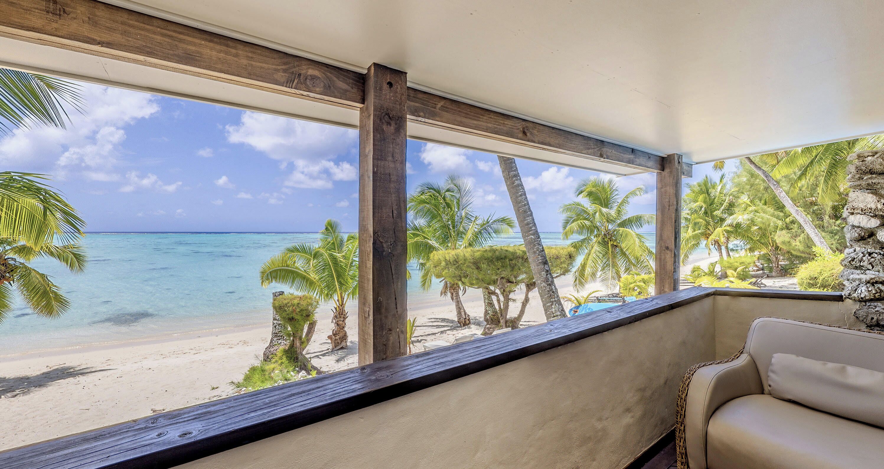 Uitzicht op het strand vanuit een kamer met een houten plafond en een beige bank.