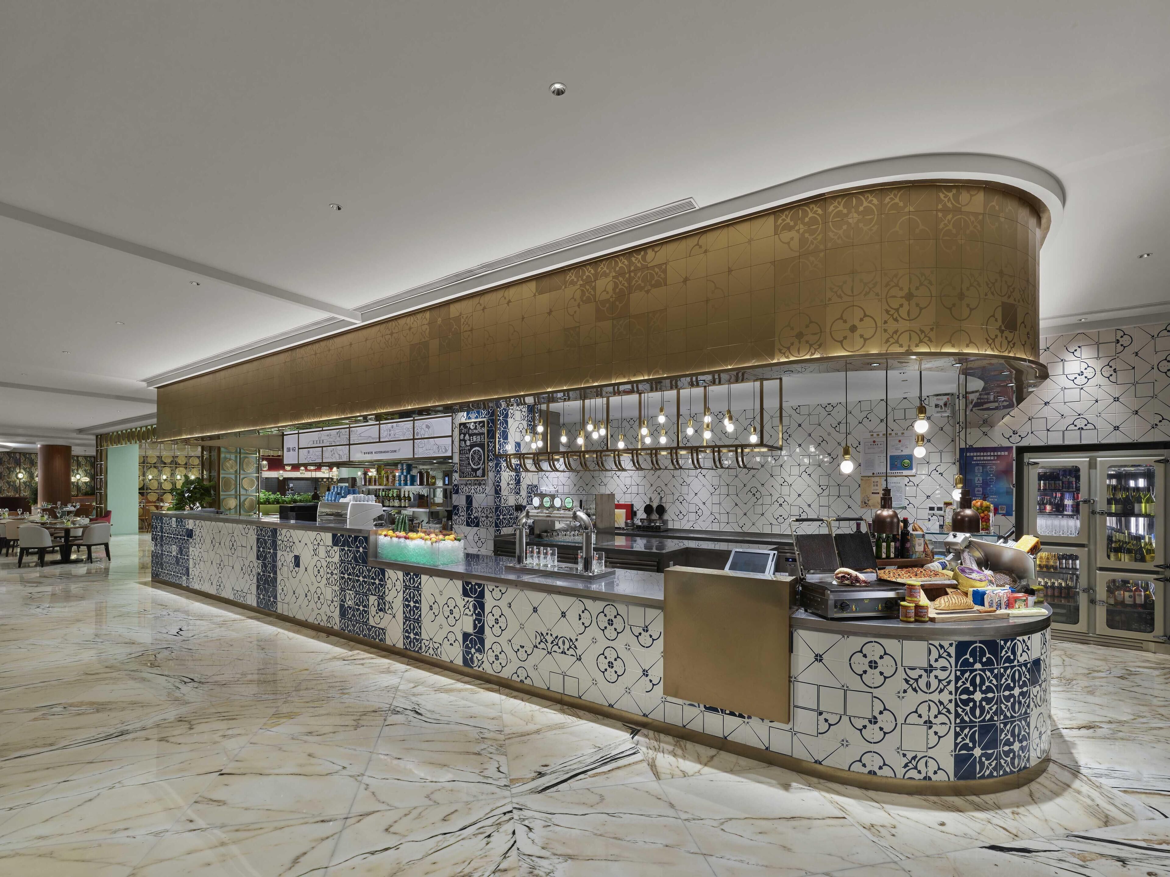 A modern bar area with a curved counter, patterned tiles, and overhead lighting.