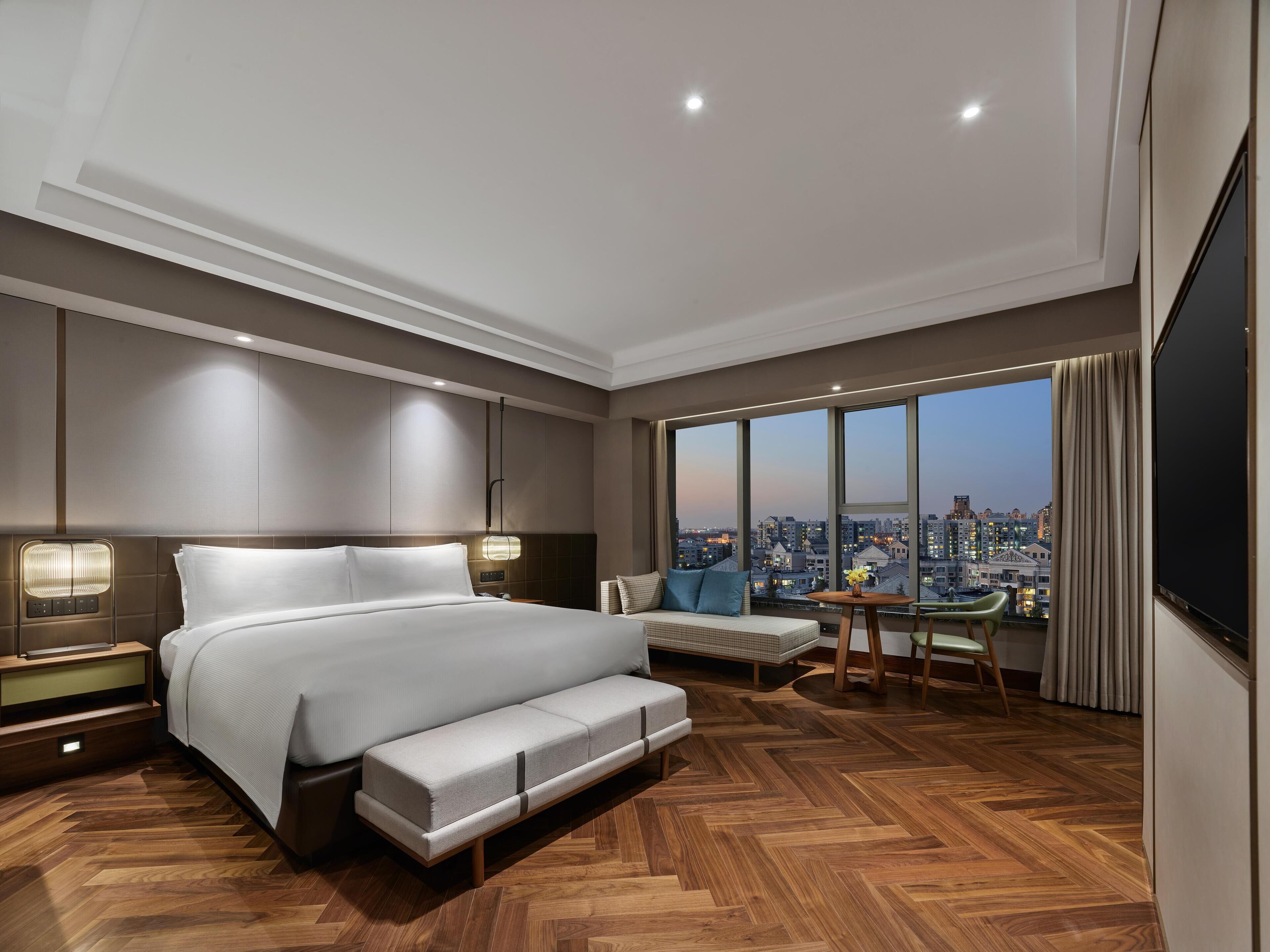 Een moderne hotelkamer met een groot bed, een zithoek en uitzicht op de stad.