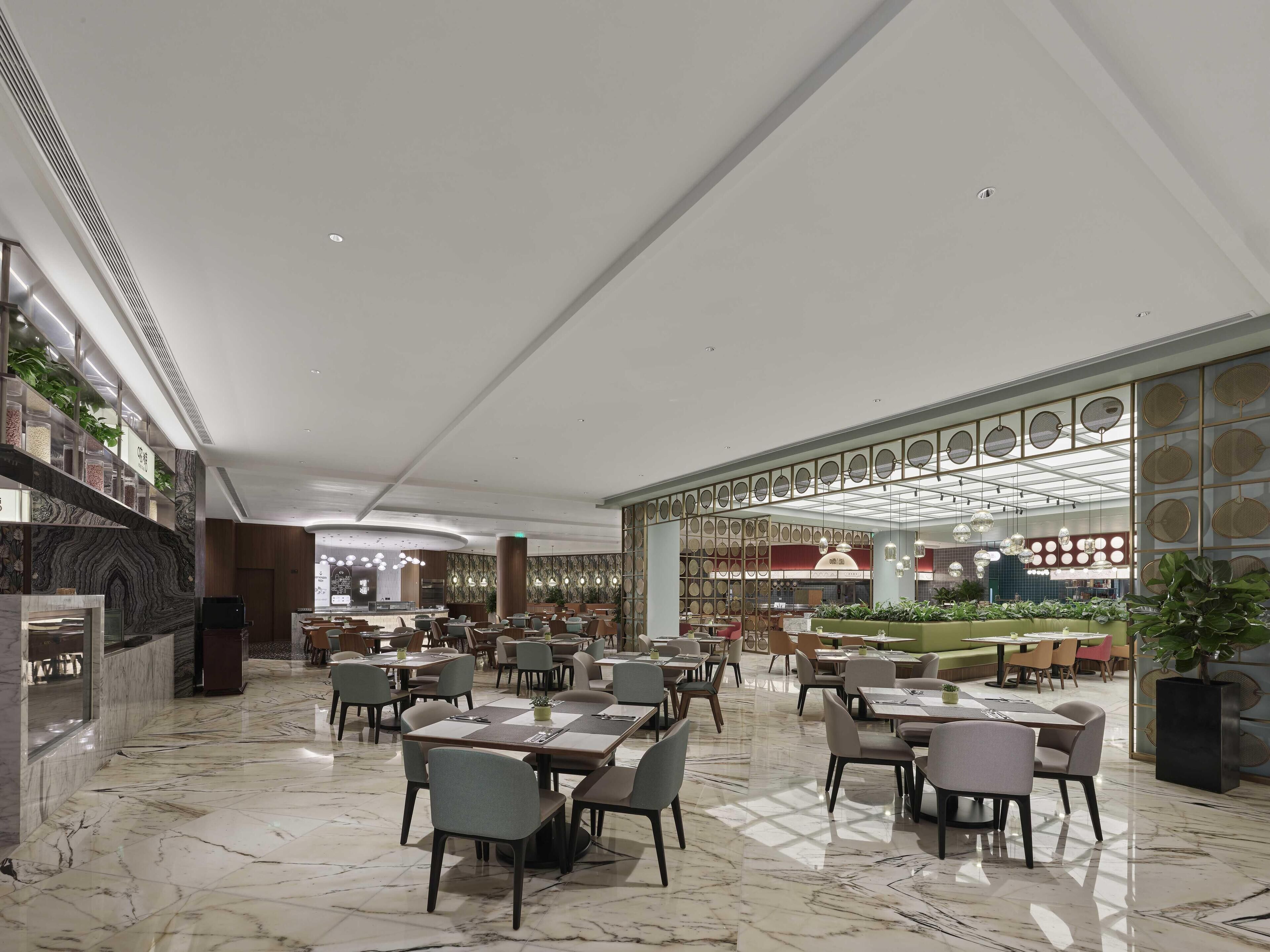 A spacious hotel lobby with marble flooring, multiple seating areas, and a central bar area.