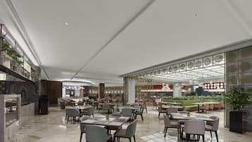 A spacious hotel lobby with marble flooring, multiple seating areas, and a central bar area.