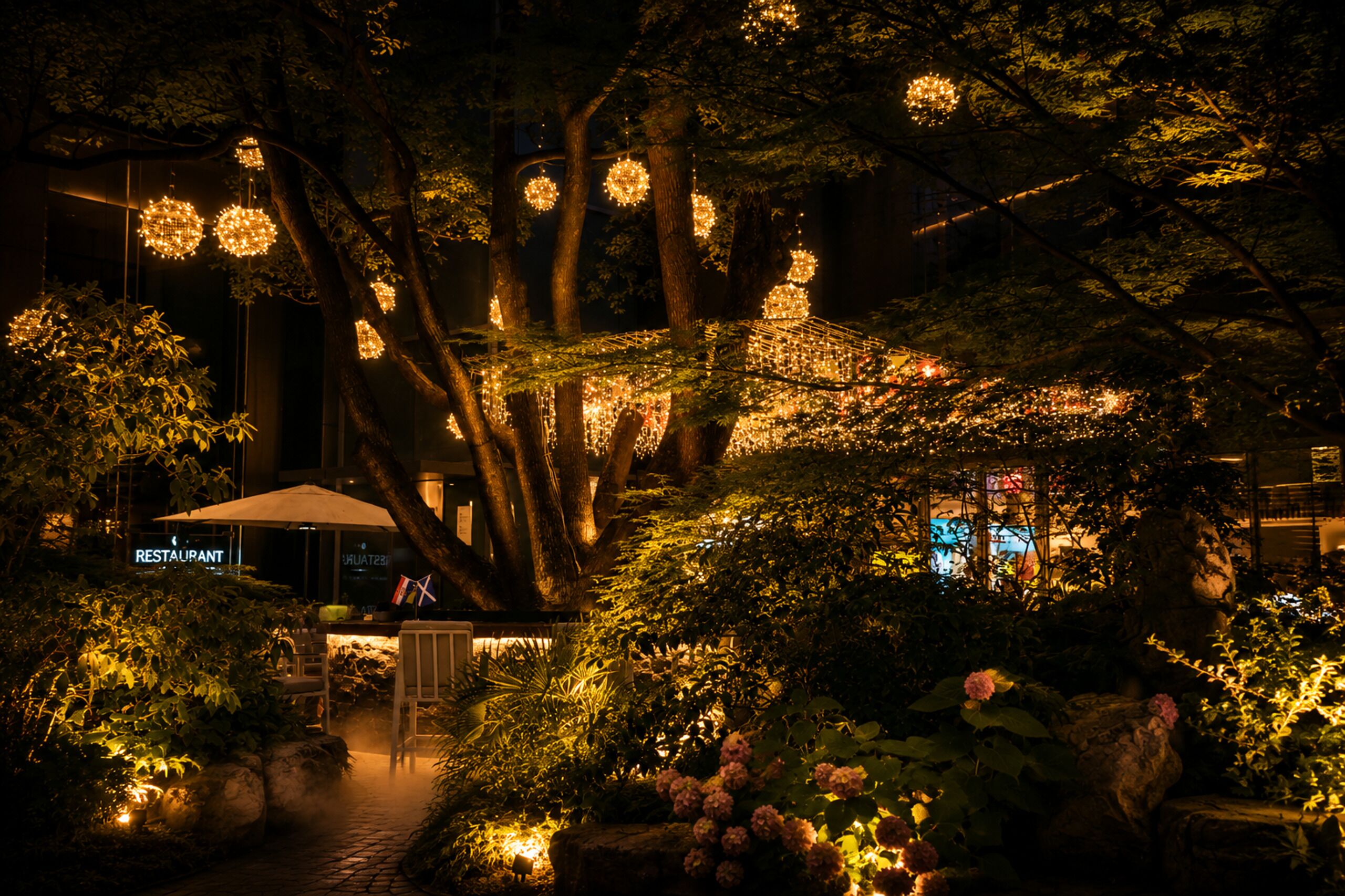 A nighttime garden with illuminated spherical lights, a restaurant sign, and a pathway leading to a gazebo.