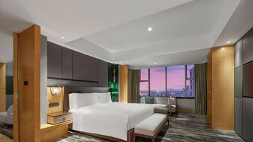 Een moderne hotelkamer met een groot bed, een bureau, een stoel, een klein tafeltje en uitzicht op de stad in de schemering.
