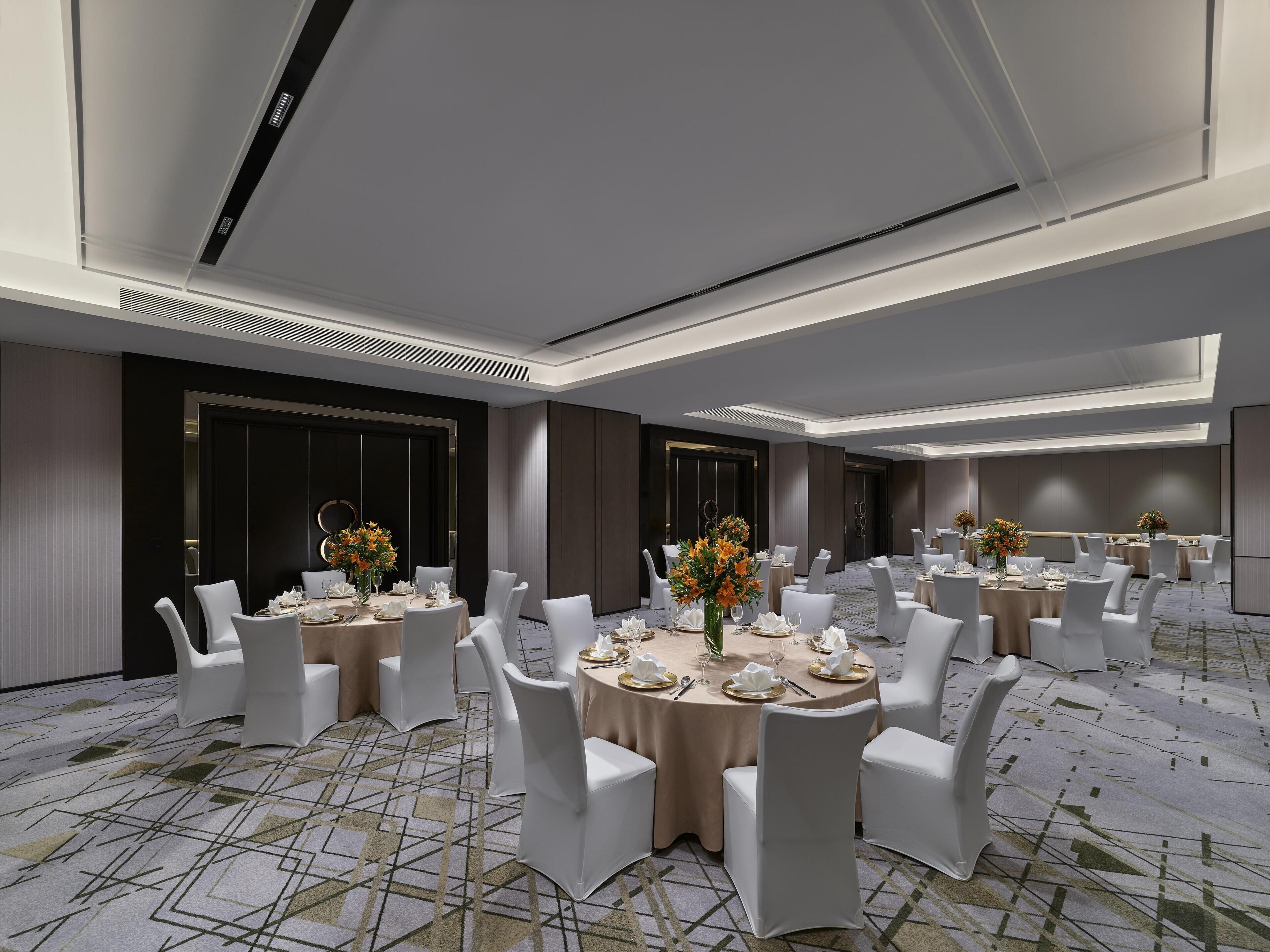 Een moderne vergaderruimte met ronde tafels, witte stoelen en bloemdecoraties.