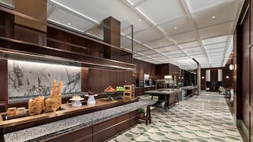 A modern hotel lobby with a long reception desk, marble wall, and patterned floor.