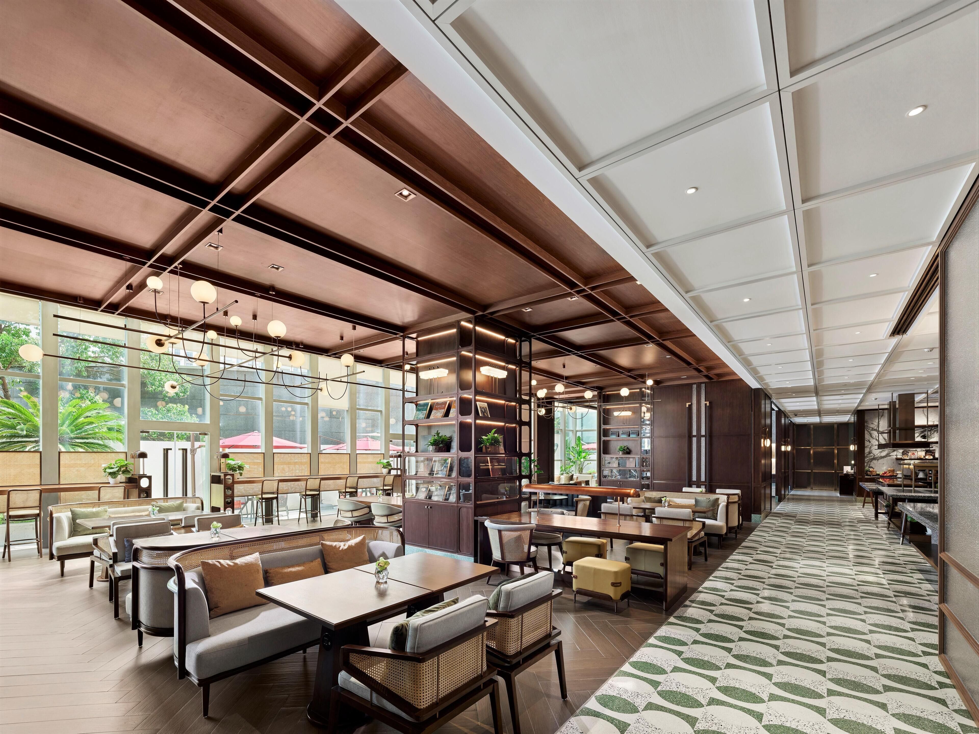 A spacious indoor area with multiple seating arrangements, including sofas and tables, and a patterned carpet.