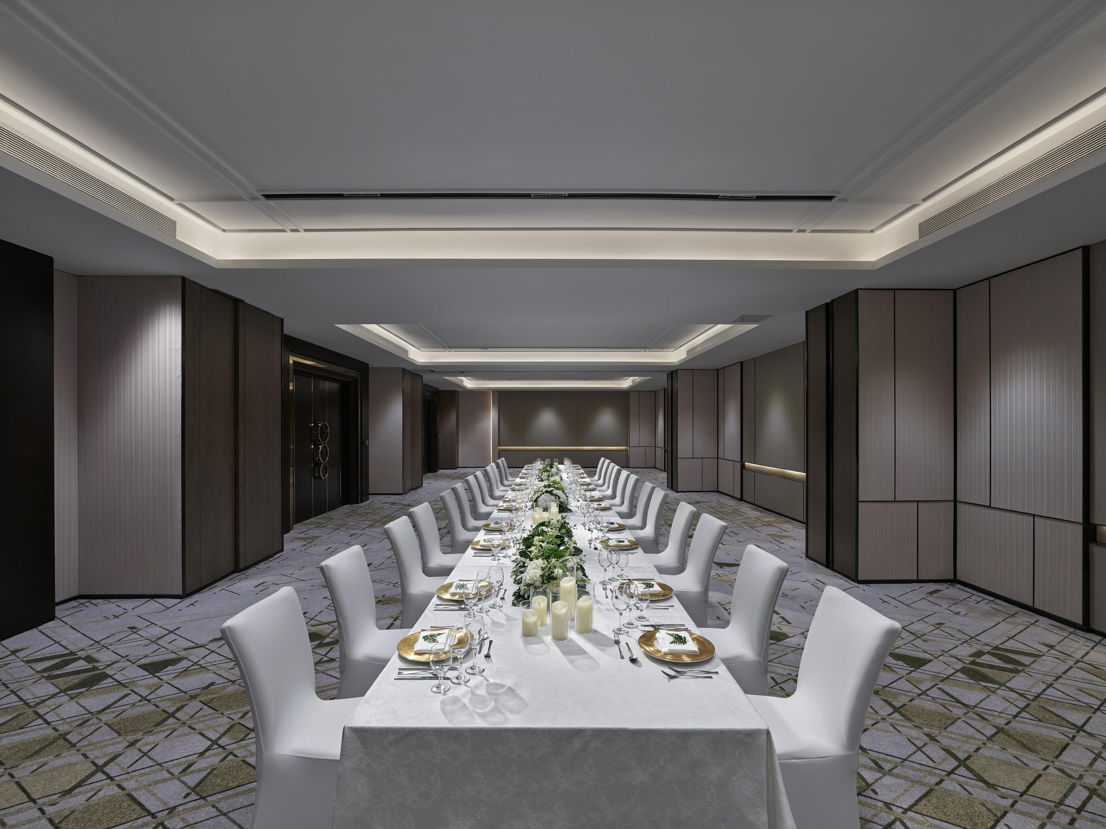 A long banquet table set for a formal event, with chairs on both sides and a decorative centerpiece.