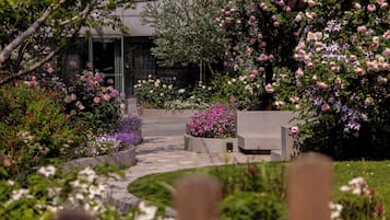 Un giardino con fiori diversi e un vialetto che conduce a un edificio.